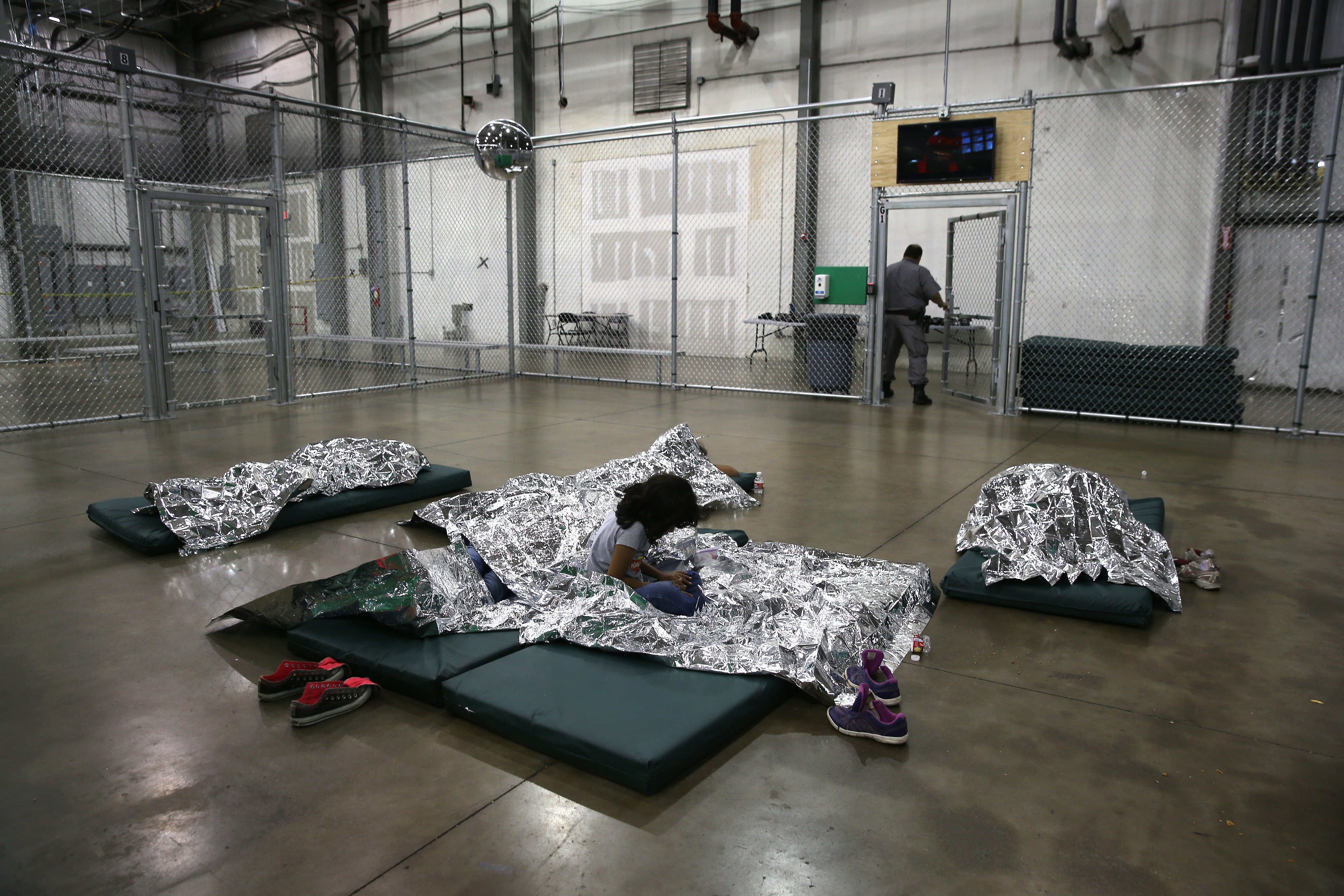 MCALLEN, TX - SEPTEMBER 08: A girl from Central America rests on thermal blankets at a detention facility run by the U.S. Border Patrol on September 8, 2014 in McAllen, Texas. The Border Patrol opened the holding center to temporarily house the children after tens of thousands of families and unaccompanied minors from Central America crossed the border illegally into the United States during the spring and summer. Although the flow of underage immigrants has since slowed greatly, thousands of them are now housed in centers around the United States as immigration courts process their cases. (Photo by John Moore/Getty Images)