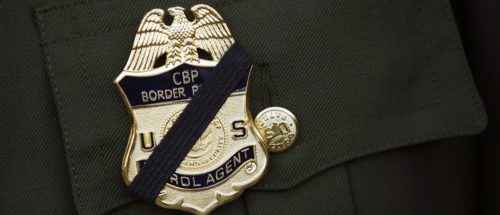 A U.S. Border Patrol agent wears a black band over his badge during a memorial service for slain comrade Brian Terry on January 21, 2011 in Tucson, Arizona. Agent Terry was killed during a December14 shootout with suspected bandits near the U.S.-Mexico Border. Thousands of Border Patrol agents and fellow law enforcement officers from across Arizona turned out for the memorial service held at Kino baseball stadium in Tucson. With U.S. agents tracking drug smugglers and illegal immigrants all along the border, the region is one of the most militarized areas of the United States. (Photo by John Moore/Getty Images)